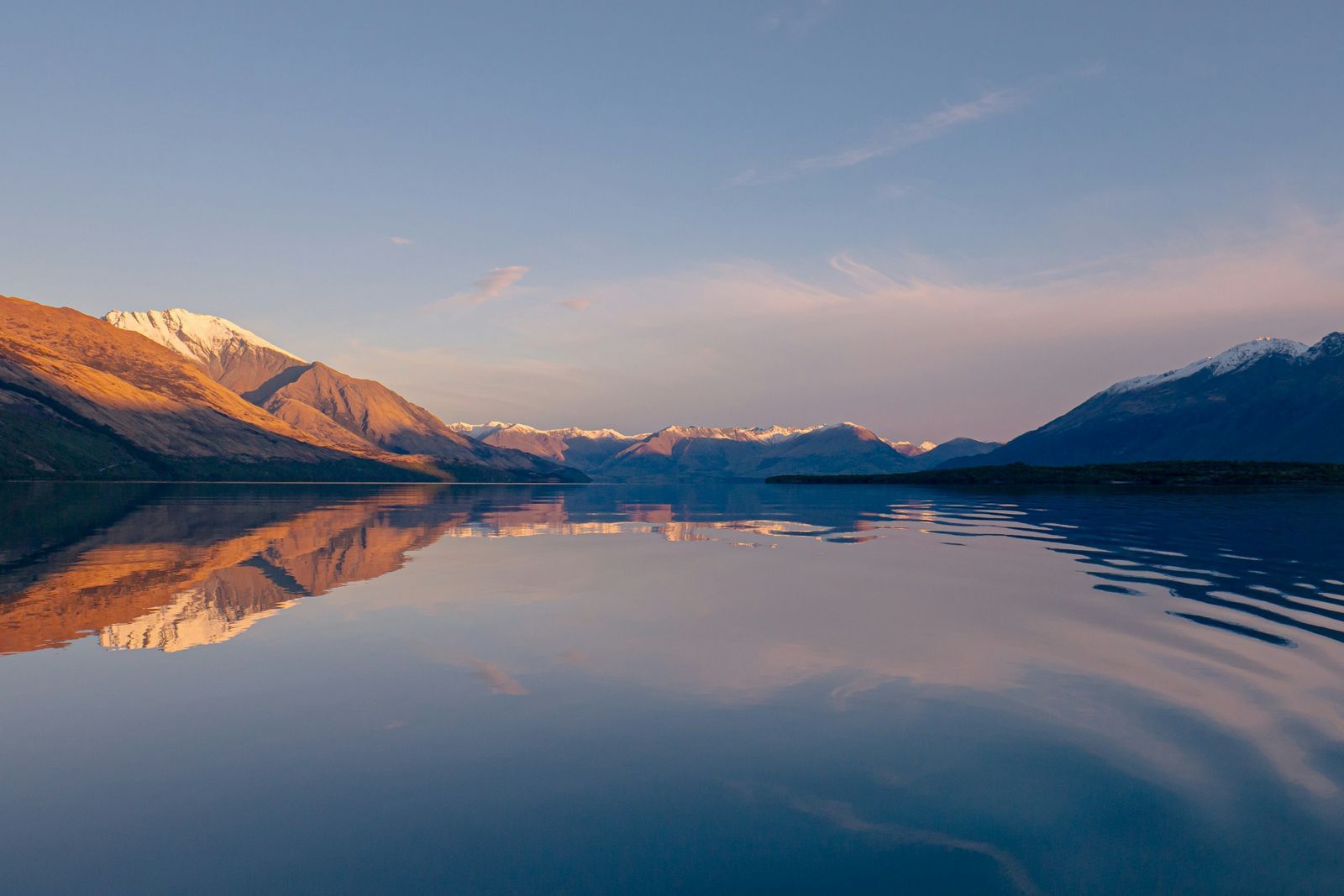 Lago en calma entre montañas al atardecer